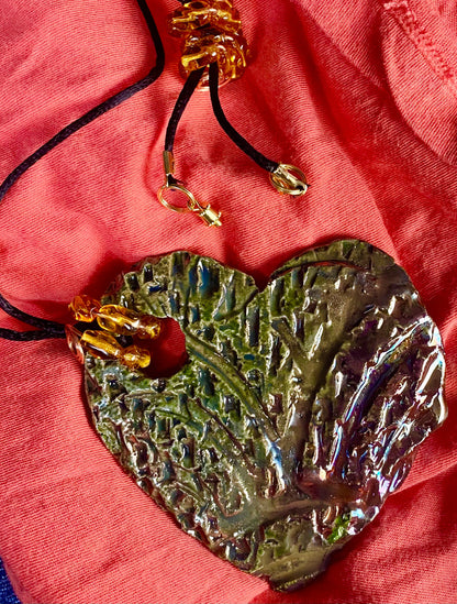 Have A Heart ! Each heart pendant is handmade with love! It is 3"x 3" and weighs approx. 3ozs. This pendant has an alligator green and gold metallic raku glazes that renders a unique translucent  patina. The heart  has a textured  pattern. It holds a spiral of amber mini beads on a spiral copper wire. This pendant has a nice 12" black suede cord!