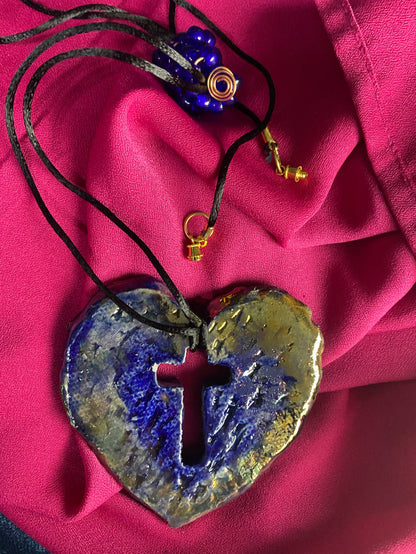 Have A Heart ! Each heart pendant is handmade with love! It is 3"x 3" and weighs approx. 3ozs. This pendant has a royal blue and gold metallic raku glazes that renders a unique translucent  patina. The heart has a cut out cross in the center with a textured  pattern. It holds a spiral of royal blue mini beads on a spiral copper wire. This pendant has a nice 12" black suede cord!