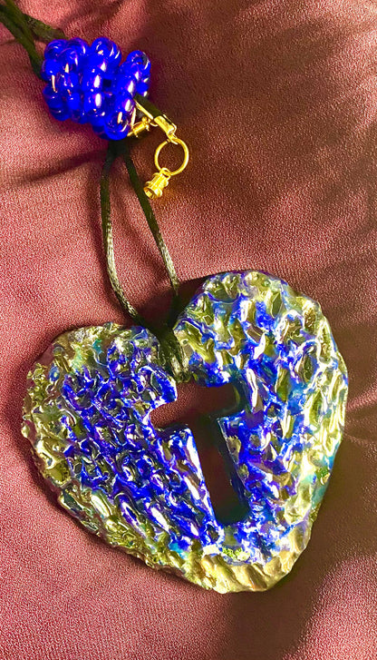 Have A Heart ! Each heart pendant is handmade with love! It is 3"x 3" and weighs approx. 3ozs. This pendant has a royal blue and gold metallic raku glazes that renders a unique translucent  patina. The heart has a cut out cross in the center with a textured  pattern. It holds a spiral of royal blue mini beads on a spiral copper wire. This pendant has a nice 12" black suede cord!