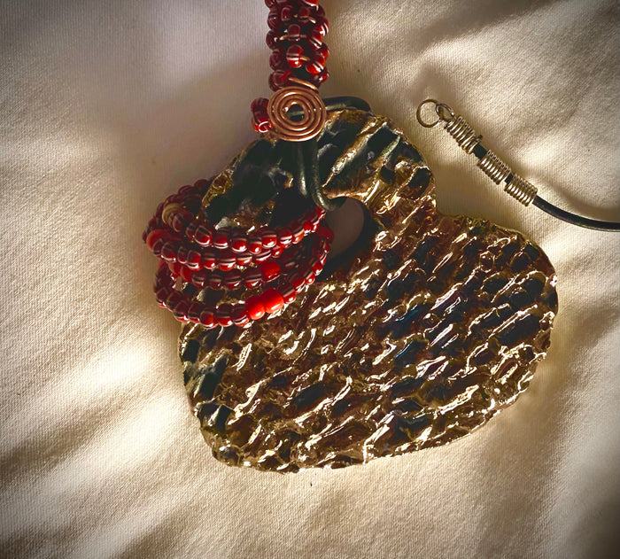 Have A Heart ! Each heart pendant is handmade with love! It is 3"x 3" and weighs approx. 3ozs. This pendant has a gold metallic raku glazes that renders a unique translucent  patina. The heart has a textured  pattern. It holds a spiral of ruby mini beads on a spiral copper wire. This pendant has a nice 12" black suede cord!
