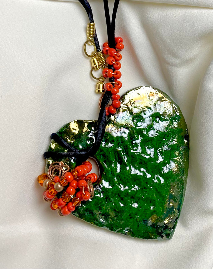 Have A Heart ! Each heart pendant is handmade with love! It is 3"x 3" and weighs approx. 3ozs. This pendant has a green metallic raku glazes that renders a unique translucent  patina. The heart has a textured pattern . It holds a spiral of green mini beads on a spiral copper wire. This pendant has a nice 12" black suede cord!