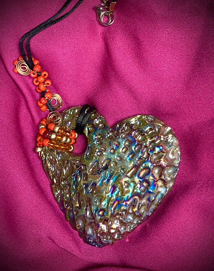 Have A Heart ! Each heart pendant is handmade with love! It is 3"x 3" and weighs approx. 3ozs. This pendant has a copper gold metallic raku glazes that renders a unique translucent  patina. The heart has a textured pattern . It holds a spiral of amber and red mini beads on a spiral copper wire. This pendant has a nice 12" black suede cord!