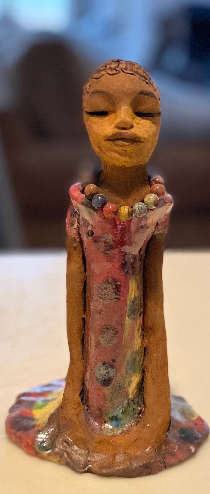 Mena long loving arms rest beside her multicolored copper green dress. Mena is a sophisticated lady that will grace your home.
