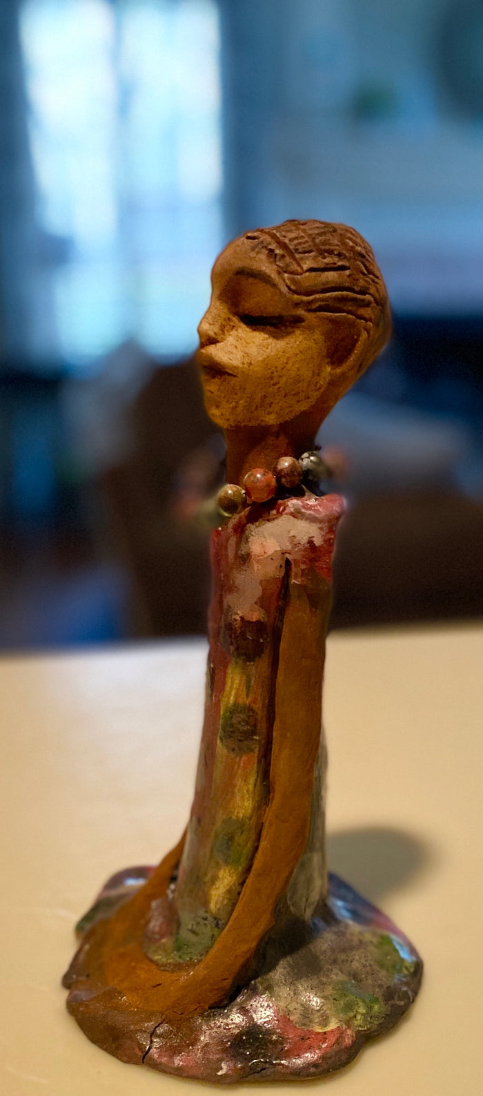 Mena long loving arms rest beside her multicolored copper green dress. Mena is a sophisticated lady that will grace your home.