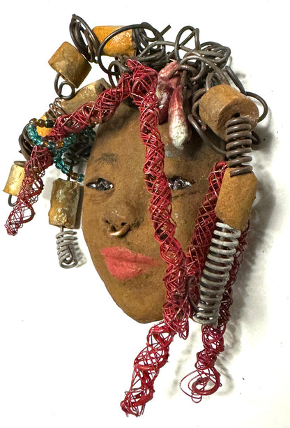 At 5" x 6" in size, Ola makes a stunning addition to walls, trees, and shadow boxes. His signature red braided hair is ornamented with handcrafted Raku beads, while his skin has a warm honey brown hue. Each piece is equipped with over 20 feet of top-notch 16 & 24-gauge wire in the hair. This fashionable sculpture will bring a modern flair to any room - simply place it in a shadow box and enjoy!