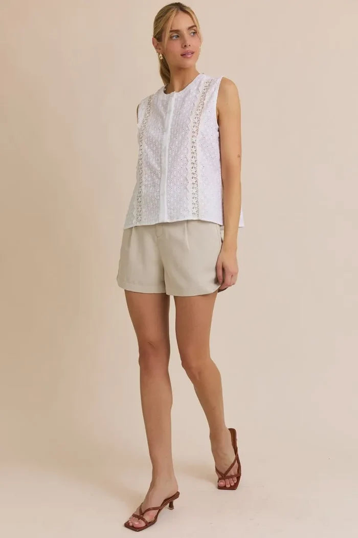 Women’s boho chic clothing featuring a sleeveless white eyelet top and beige shorts